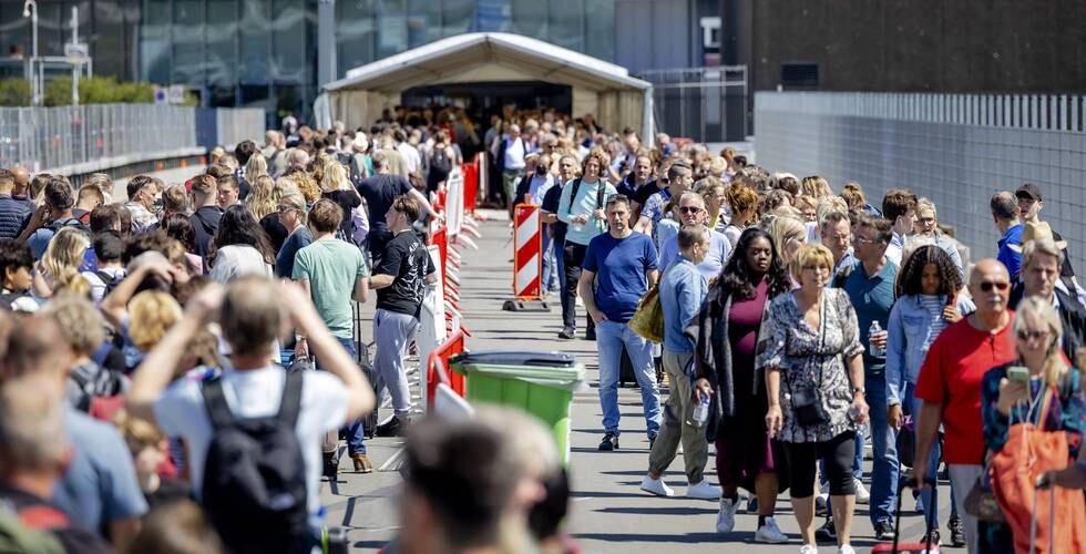 Bilder av folk som står i en lang kø på utsiden av Schiphol lufthavn. De står i kø for å få slippe inn på flyplassen. Foto: Robin van Lonkhuijsen / ANP / APF / NTB