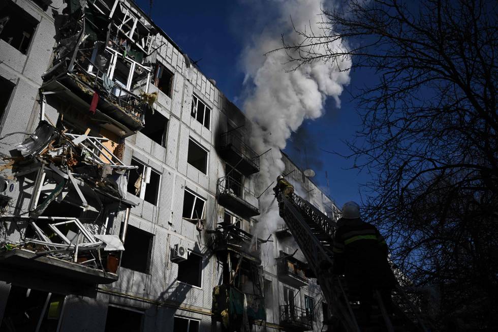Bildet er av brannfolk som prøver å slukke en brann i en bygning. Den skal være truffet i et angrep fra Russland mot Ukraina. Bildet er fra byen Chuguiv. Foto:  Aris Messinis / AFP / NTB