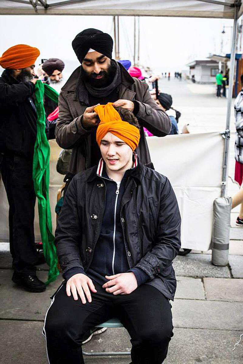 Bildet viser en gutt som får surret en turban rundt hodet sitt.