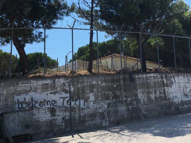Bildet viser muren utenfor flyktningleiren Moria.  «Velkommen til fengsel» står det sprayet på veggen.