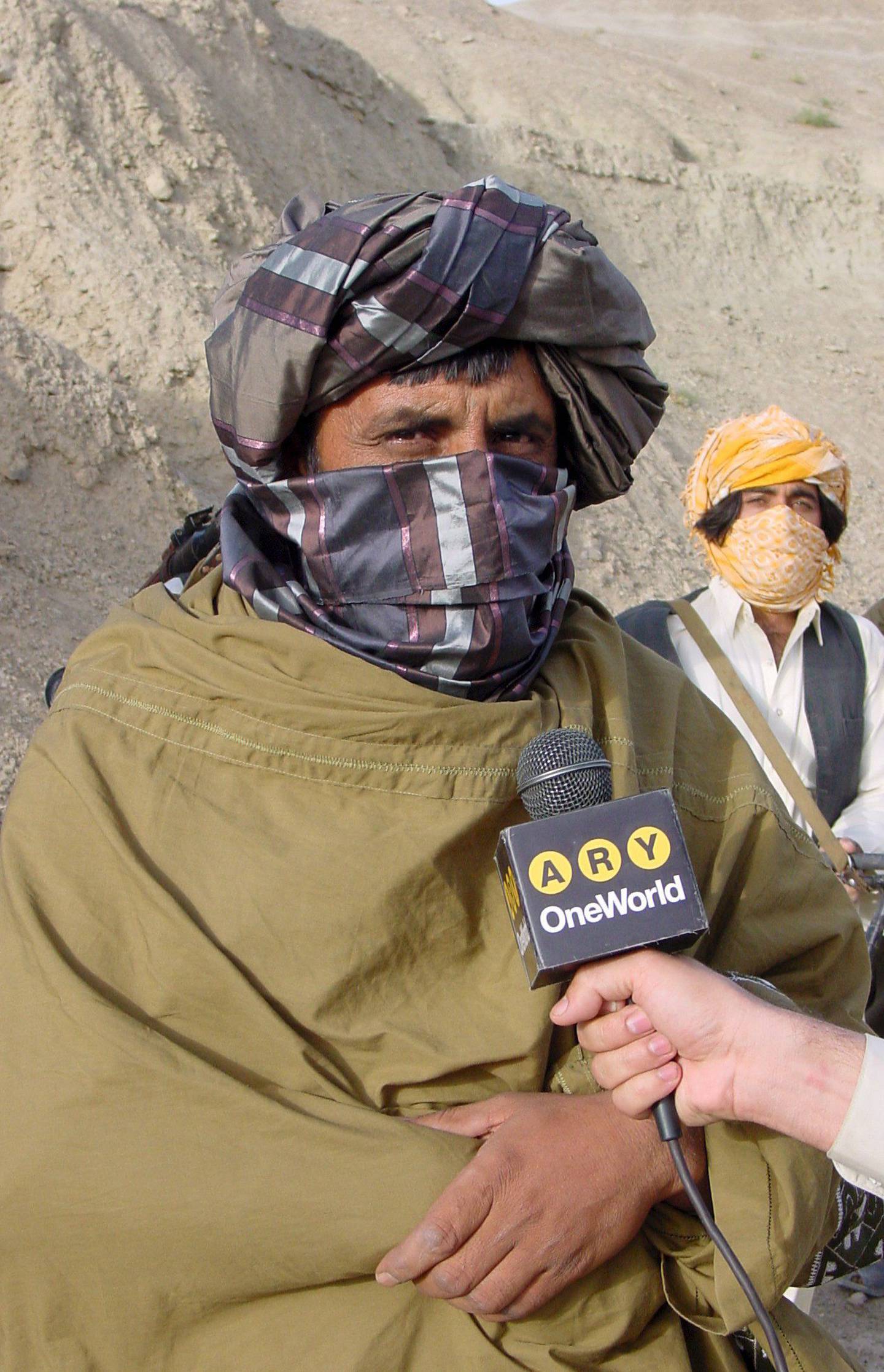 Bildet er av Zabiullah Mujahid i 2008.  Han snakker i en mikrofon fra en journalister i et fjellområde i Afghanistan. Foto: EPA / NTB
