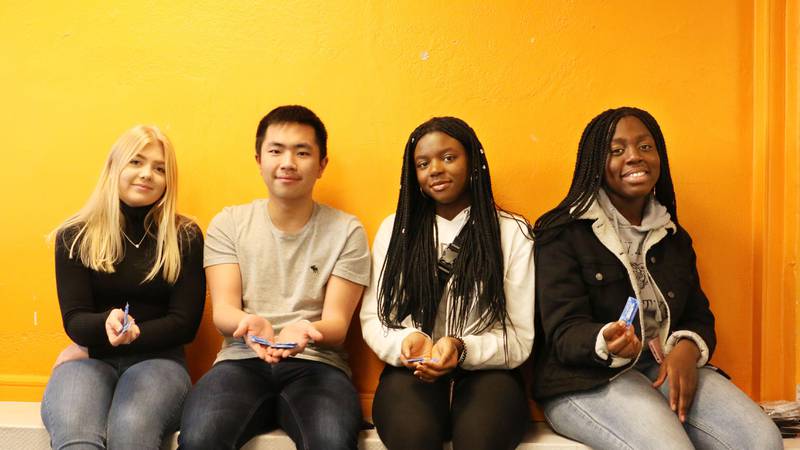Bildet viser fire ungdommer som sitter og holder kondomer.