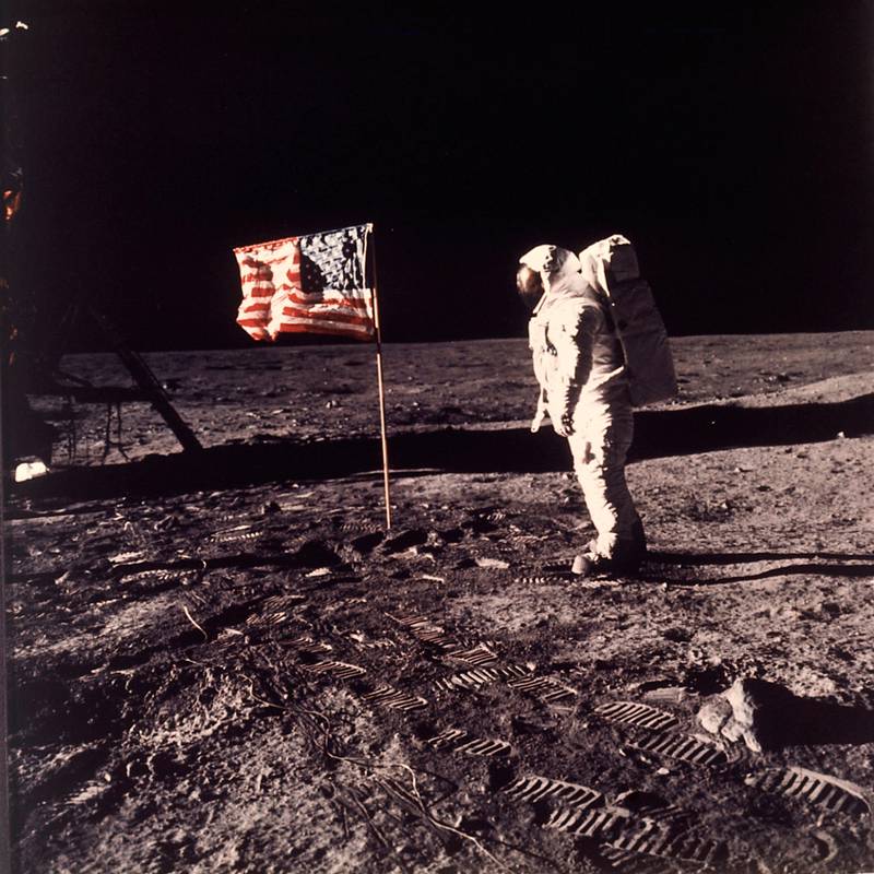 Bildet viser astronauten Buzz Aldrin i romdrakt på månen. Han står ved et amerikansk flagg.