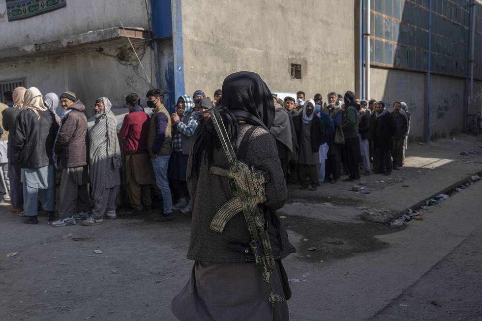 Bildet viser en Taliban-kriger som sikrer området der folk står i kø for å få mat. Bildet er fra Kabul i Afghanistan. Foto: Petros Giannakouris / AP / NTB