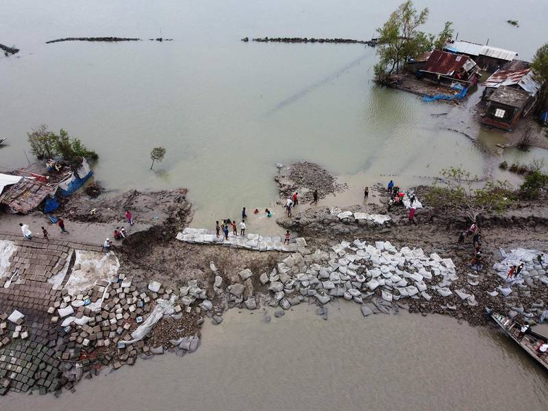 An aerial view shows volunteers and residents working to fix a damaged dam following the landfall of cyclone Amphan in Burigoalini on May 21, 2020. - At least 84 people died as the fiercest cyclone to hit parts of Bangladesh and eastern India this century sent trees flying and flattened houses, with millions crammed into shelters despite the risk of coronavirus. (Photo by Munir uz Zaman / AFP)