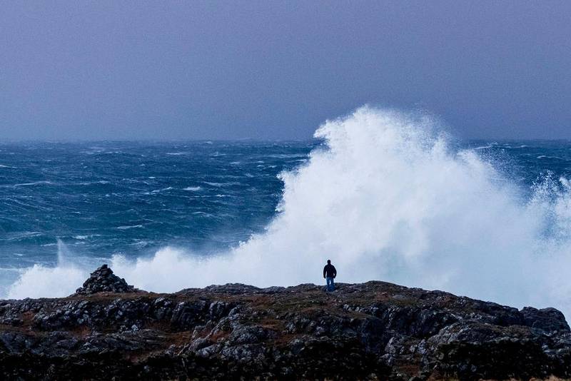 Bildet viser en mann som ser på høye bølger.