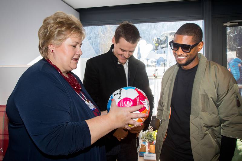Bildet viser Erna Solberg som gir en fotball til artisten Usher.