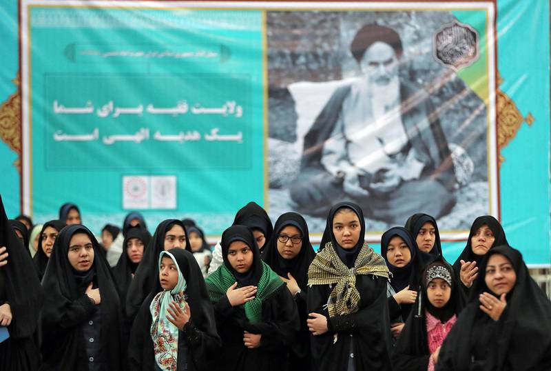 Bilder viser kvinner som ber foran et bilde av Khomeini.