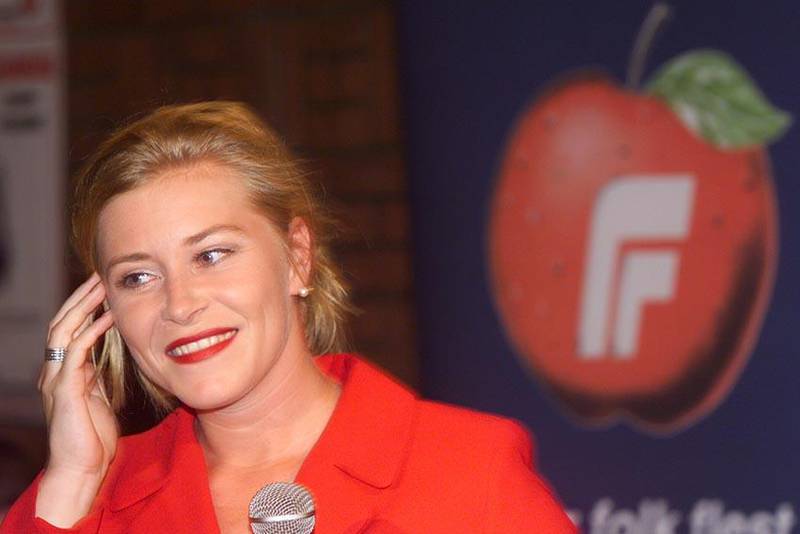 Bildet viser Siv Jensen som smiler foran Frps logo.