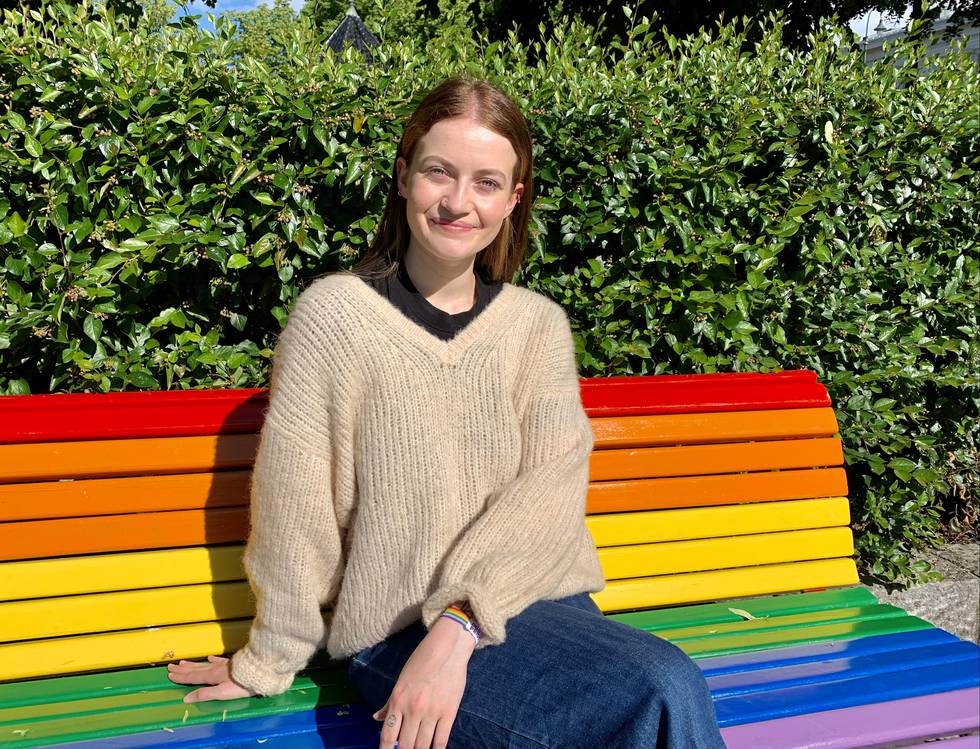 Julia Beatrice Reksten sitter på en regnbue-benk.