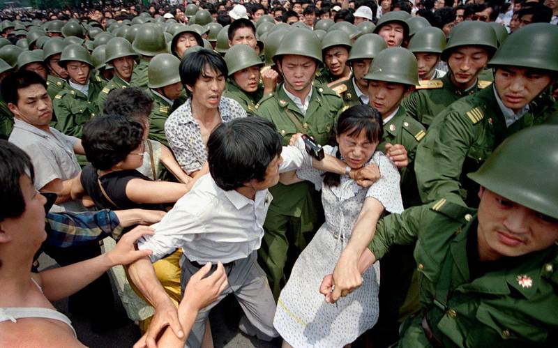 Bildet viser en kvinne som rives mellom militære og sivile i Beijing i Kina i 1989.