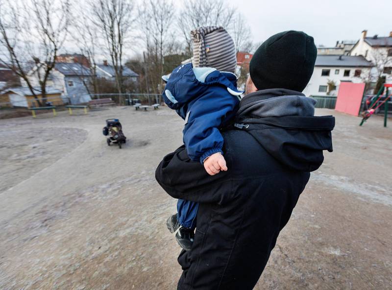 Bildet viser en pappa med et barn på armen.