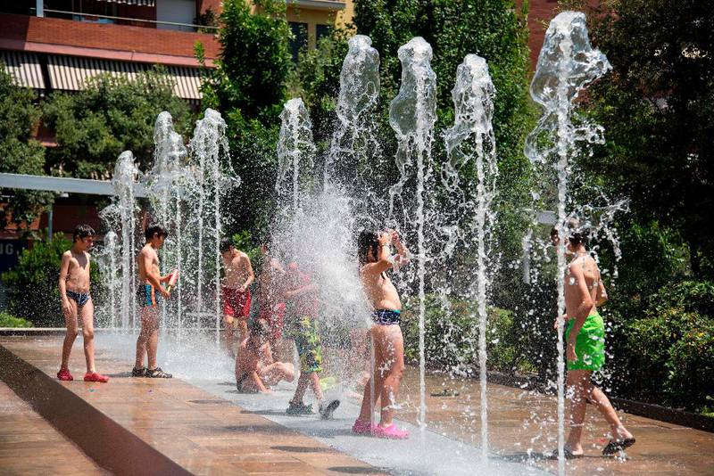 Bildet viser barn som leker i vannfontener i Barcelona i Spania 18. juni.