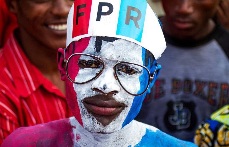 Bildet viser en mann som har malt ansiktet rødt, hvitt og blått. Han har bokstavene RPF på en hatt. Han støtter partiet Rwandas patriotiske front (RPF).