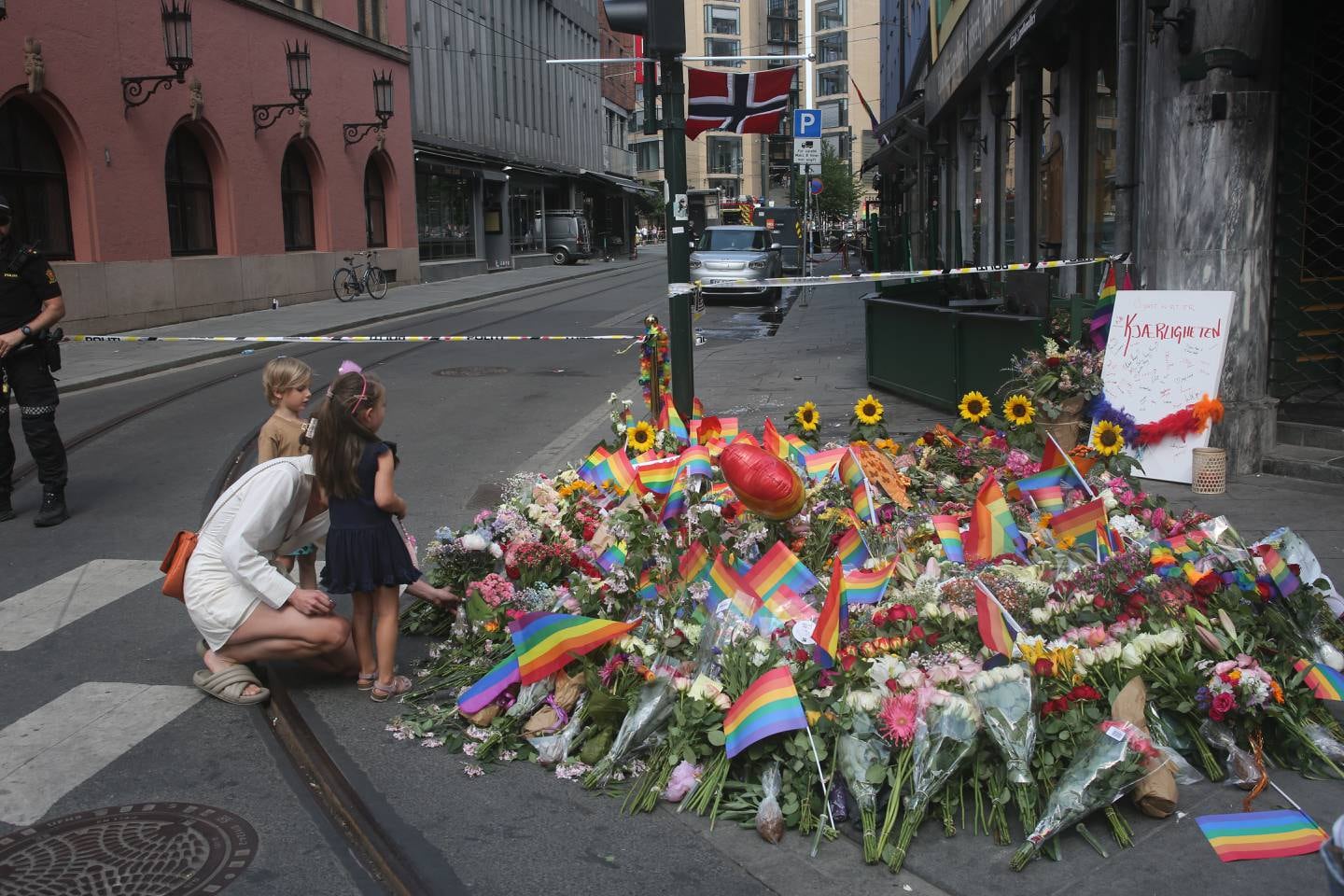 Bildet viser To barn og mødrene deres legger ned blomster ved London Pub i Oslo. To menn ble drept her og 21 mennesker skadd. Det skjedde natt til lørdag.