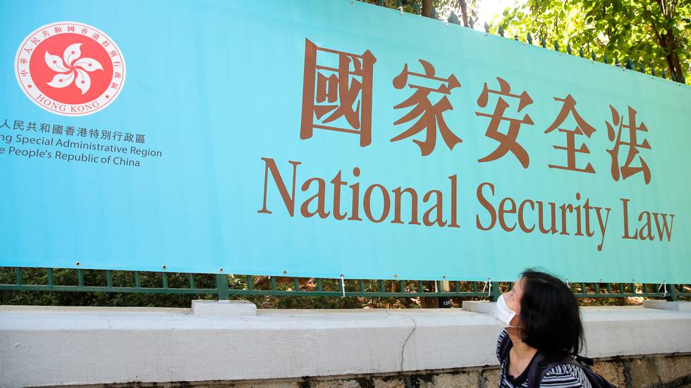 Bildet viser en kvinne som ser opp på en stor plakat hvor det står skrevet National Security Law.