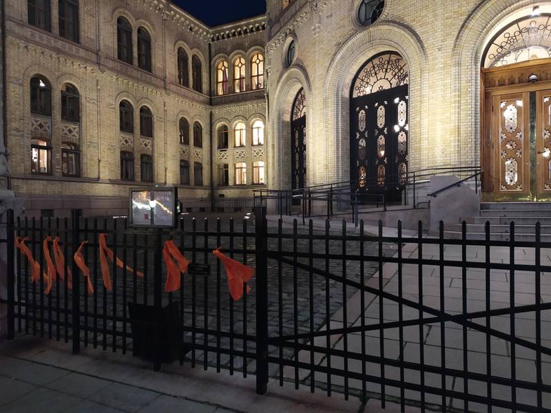 Oransje tøystykker som er knyttet fast til porten til Stortinget