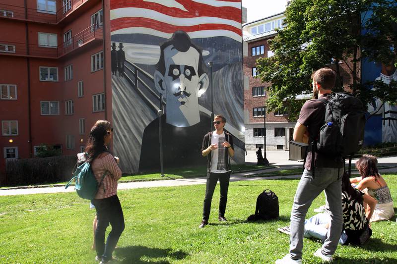 James Finucan i Oslo Street Art Tours på et av omvisningens obligatoriske stoppesteder, Steffen Kverneland og Monica Tellnes' Munch-maleri fra 2015. Til høyre et glimt av Fadlabis store veggmaleri. Foto: Gitte Johannessen / NTB