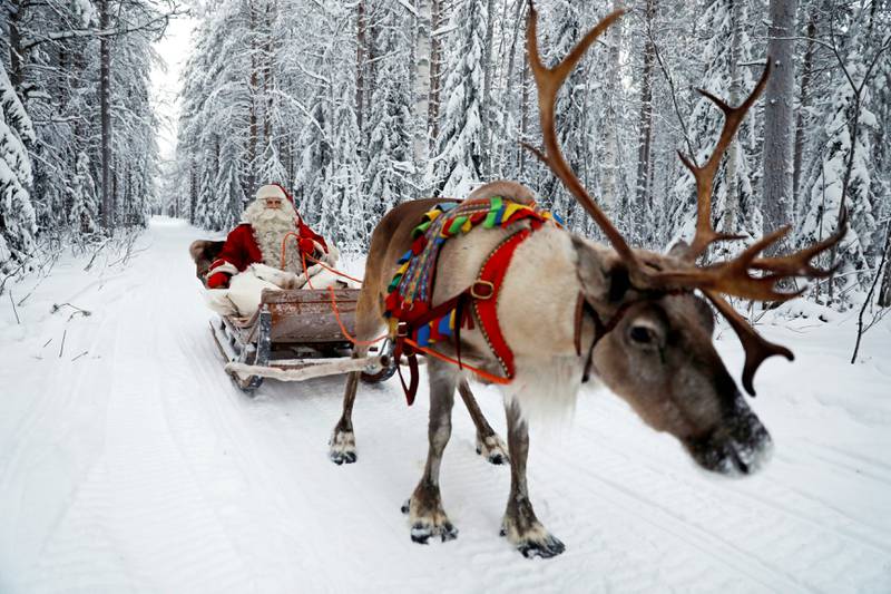 Bildet viser en julenisse som kjører slede med reinsdyr.