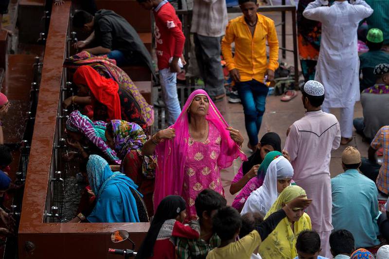 Bildet viser en indisk kvinne med rosa sjal. Hun forbereder bønn.