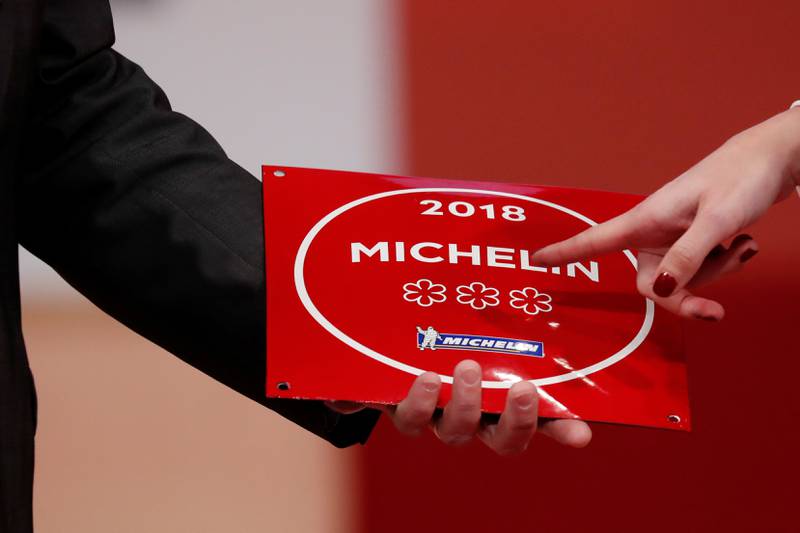 Bildet viser noen som holder opp en Michelin-plakett med tre stjerner.