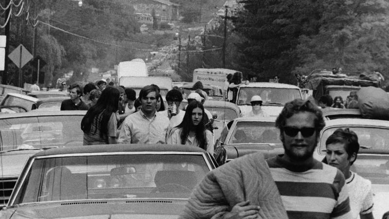 Bildet viser folk som går langs en vei for å nå Woodstock-festivalen.