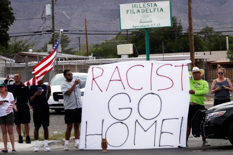 Bildet viser to menn som holder en plakat mot president Trump i El Paso i USA.