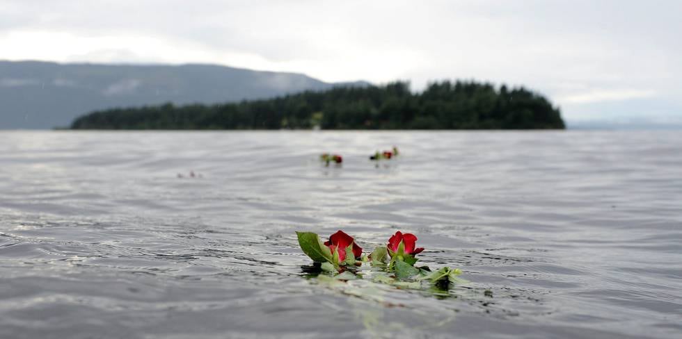 Røde roser ligger i vannet og vi ser Utøya i bakgrunnen.