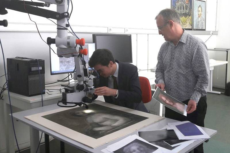 Bildet viser to eksperter som undersøker den nakne Mona Lisa.