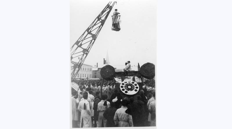 Bildet viser studenter på torget under UKA 1937. En stor telefon er med i paraden. Formannen taler fra toppen av en kran.