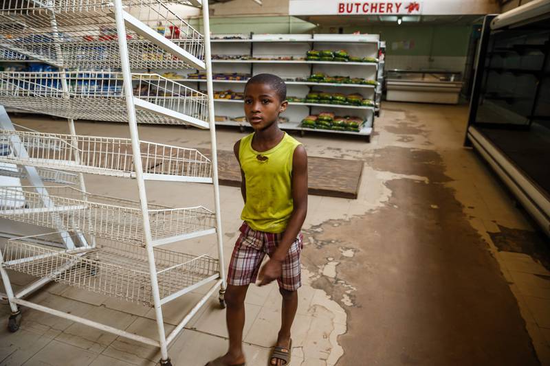 Bildet viser en gutt ved tomme butikkhyller i Zimbabwe.