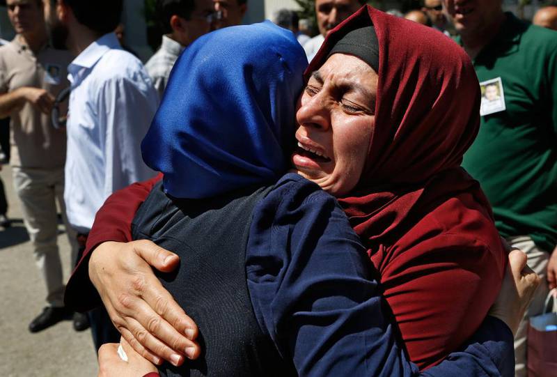 Bildet viser to kvinner som gråter og klemmer hverandre under en begravelse i Tyrkia.