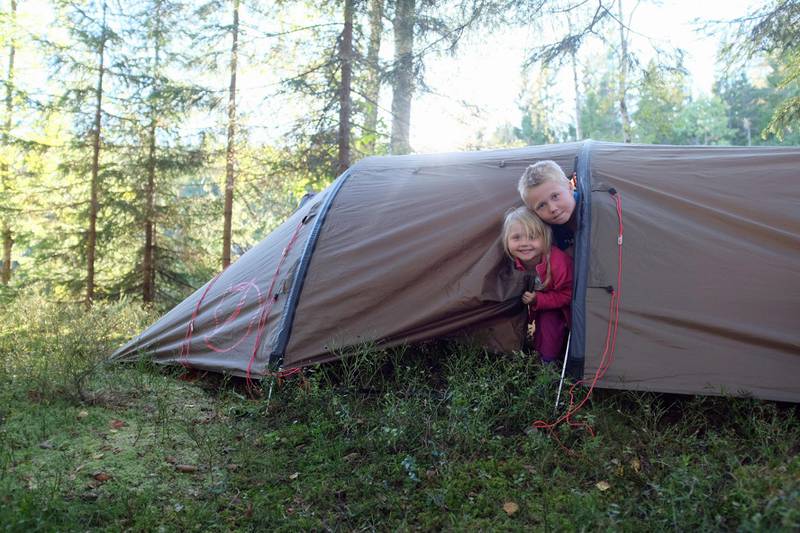 Bildet viser to barn ved et telt.