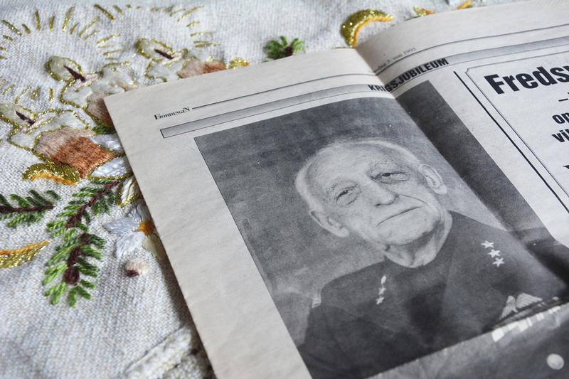 Bildet viser en avis med et fotografi som ligger på et bord.