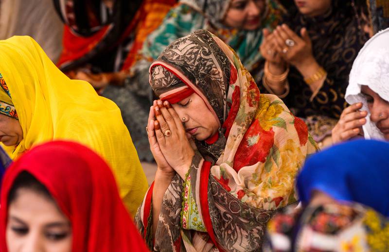 Bildet viser en festkledd kvinne som ber.