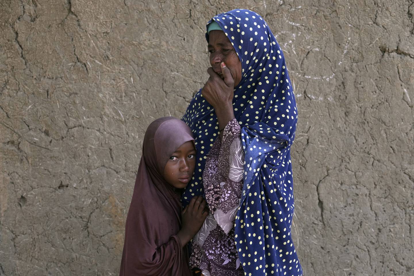 Aisha Ali prøver å trøste datteren Husseina på ni år. Hun mistet tvillingsøsteren sin og tre andre søsken da flomvannet veltet oksekjerren de satt på. Nå er livet blitt svært vanskelig, og Husseina savner søsteren sin veldig. Foto: Sunday Alamba / AP / NTB