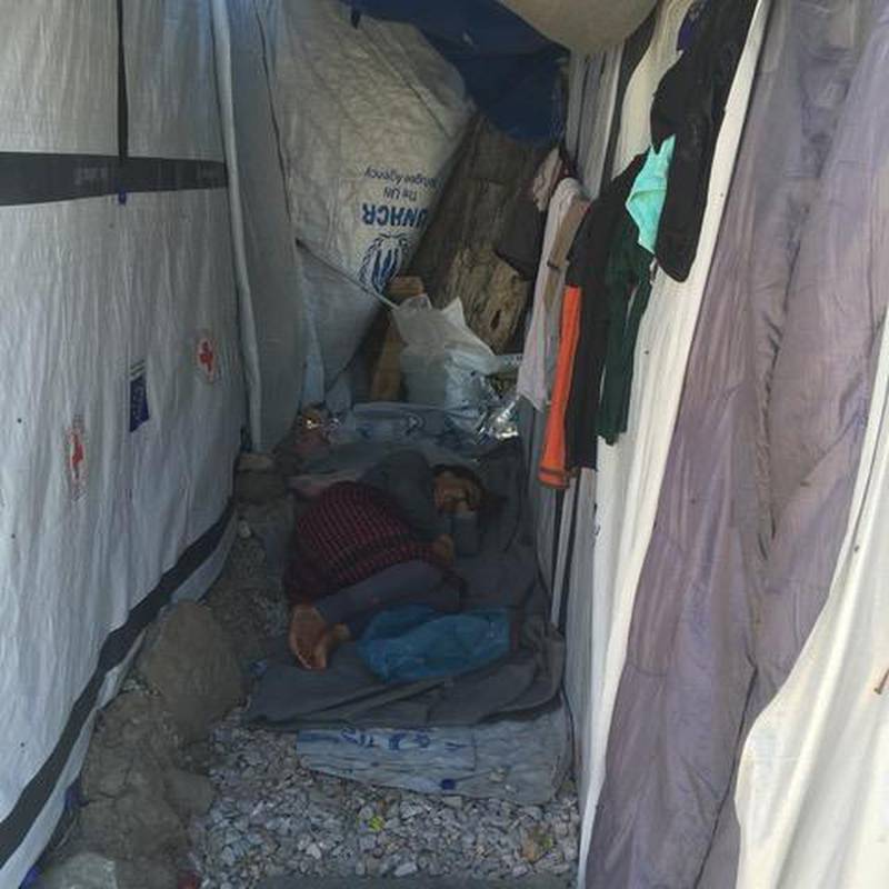 Bildet viser en kvinne som ligger og sover i et telt i flyktningleiren Moria. Hun ligger på et pledd rett på bakken. Også gravide i leiren må sove slik.