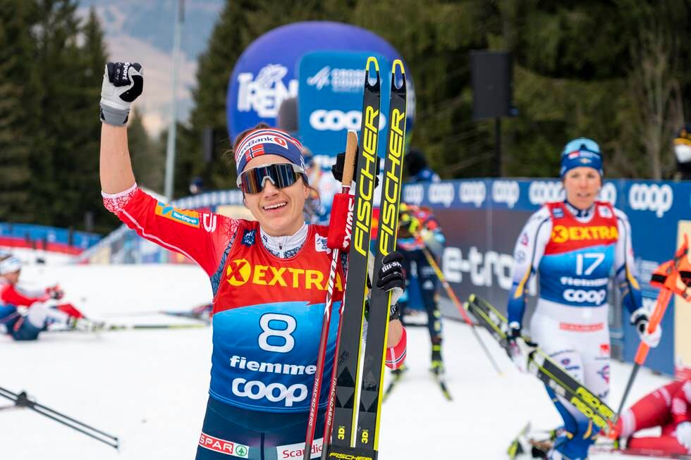Bildet er av skiløperen Heidi Weng som jubler for en seier. Flere andre skiløpere går ved siden av eller sitter i bakgrunnen. Weng har løftet en arm i været og smiler. Hun har på solbriller. Foto: Terje Pedersen / NTB