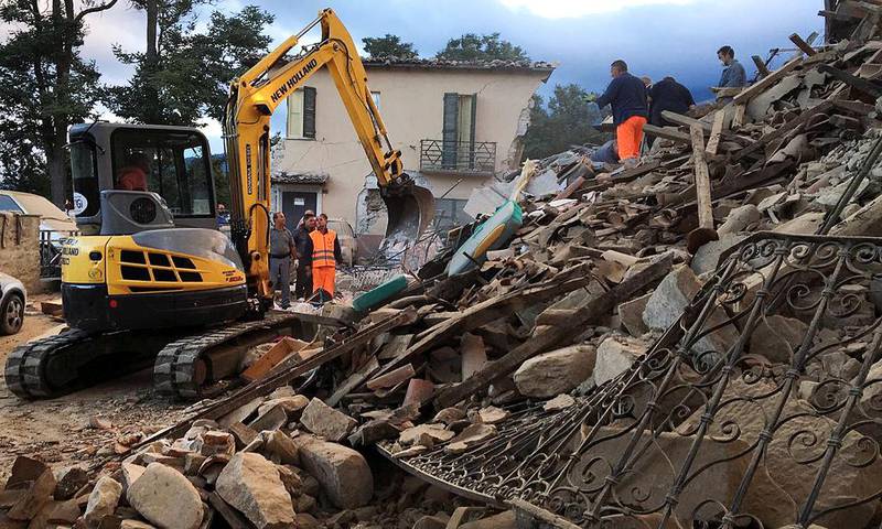 Arbeidere jobber i et hus som har falt sammen i Amatrice. 