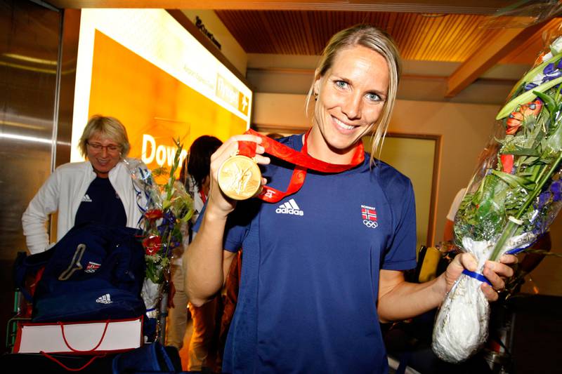 Bildet viser håndballspilleren Gro Hammerseng som smiler og viser fram gullmedaljen fra OL i 2008.