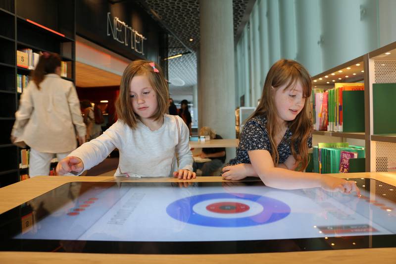 Bildet er av to jenter som bruker en interaktiv skjerm.
