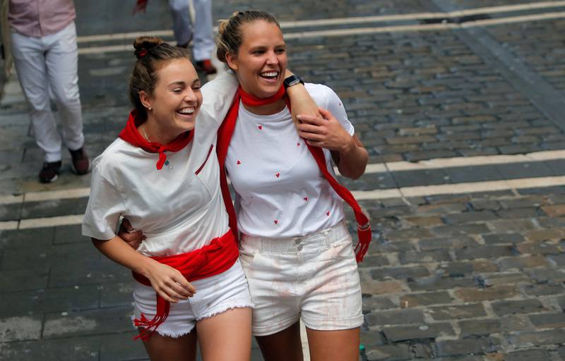 Bildet viser to kvinner som ler etter et okseløp i Pamplona.