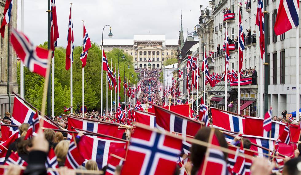 Bildet viser norske flagg og 17. mai tog. På tirsdag er det Norges nasjonaldag. Værmeldingen varierer for hvor i Norge du skal være.