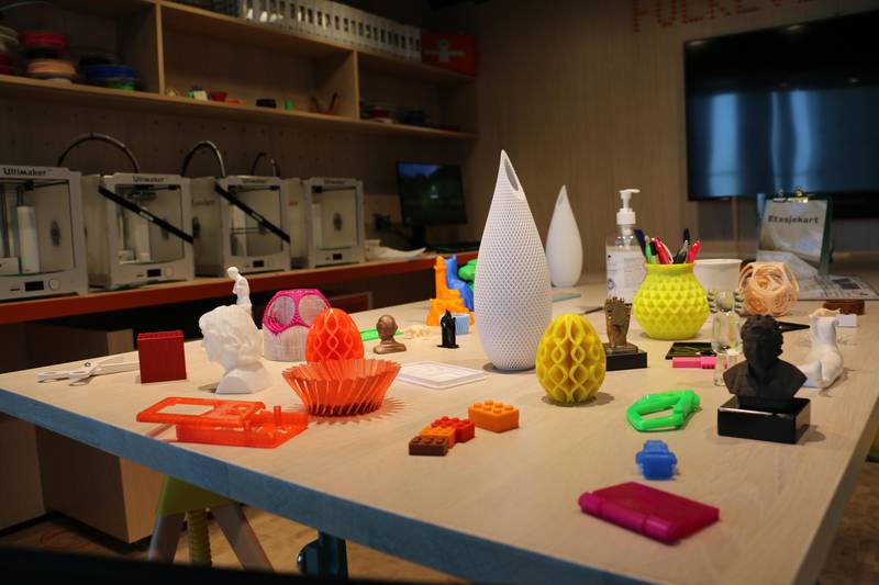 Bildet viser ulike ting folk kan lage på biblioteket. Det er laget med en 3D-printer. Den lager ting i både høyde, bredde og lengde. Slik kan den skrive ut vaser, skåler og andre ting.