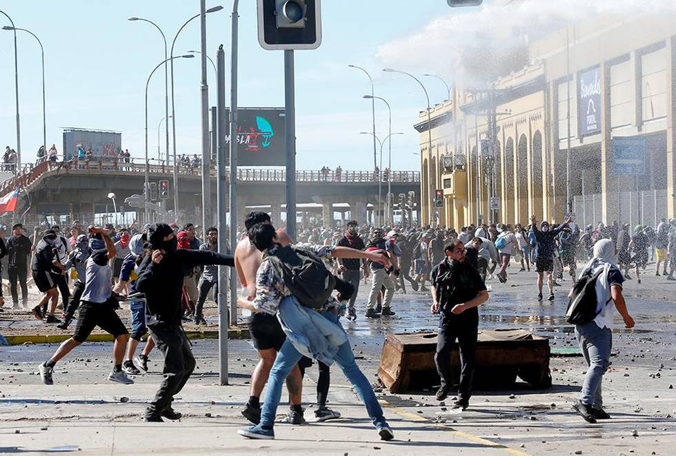 Bildet viser demonstranter i Chile som kaster ting.