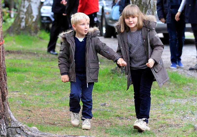Bildet er av prinsesse Ingrid Alexandra og prins Sverre Magnus. De to barna har like jakker, og går på gresset mens de holder hverandre i hendene. Foto: Cornelius Poppe / NTB .