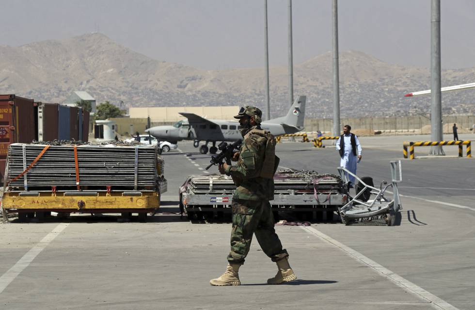 En Taliban-soldat holder vakt på rullebanen på flyplassen i Kabul. Foto: Wali Sabawoon / AP / NTB