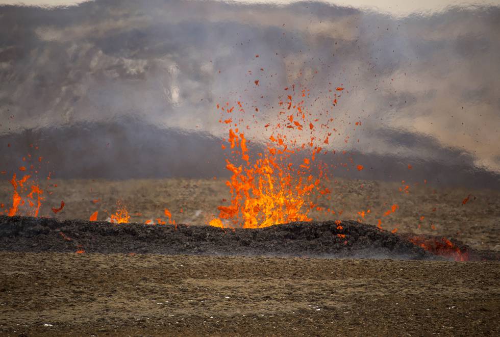 Bildet er av små utbrudd av lava fra bakken. Det ser ut som noen under bakken spytter den opp. Terrenget rundt er goldt. Foto: Marco Di Marco / AP / NTB