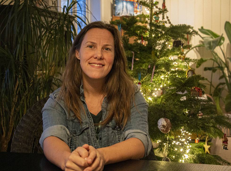 Birgit Liodden sitter på middagsbordet sitt med juletre i bakgrunnen.
