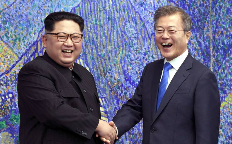 Bildet viser Kim Jong-un fra Nord-Korea som tar Sør-Koreas president Moon Jae-in i hånden. De ser glade ut. 